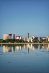 Buildings by lake against blue sky