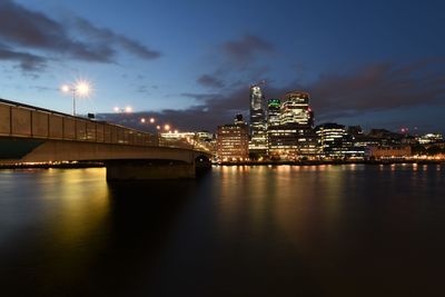 Illuminated bridge over river in city at night