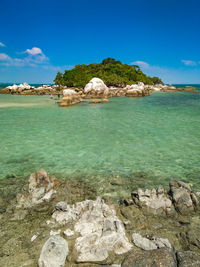 Scenic view of rocks in sea against blue sky