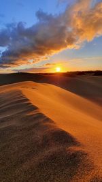 Scenic view of dunes against sunset 