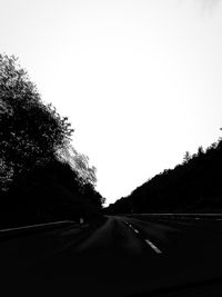 Road amidst trees against clear sky