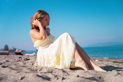Low angle view of woman sitting on sand at beach