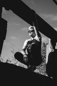 Low angle view of woman sitting against sky