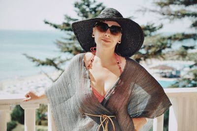 Portrait of woman wearing hat and sunglasses against sea