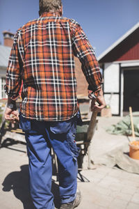 Rear view of senior man pushing wheelbarrow at yard