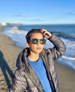 Portrait of young boy wearing sunglasses while standing at beach