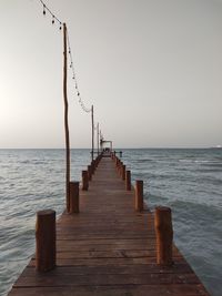 Wooden jetty in sea against clear sky