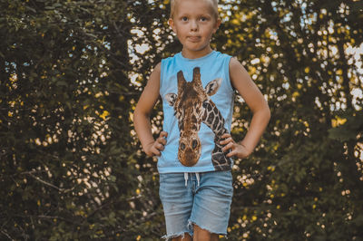 Portrait of boy holding plant against trees