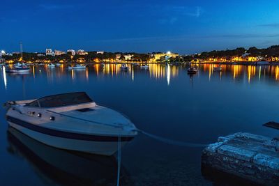 Boats moored in harbor by sea against blue sky