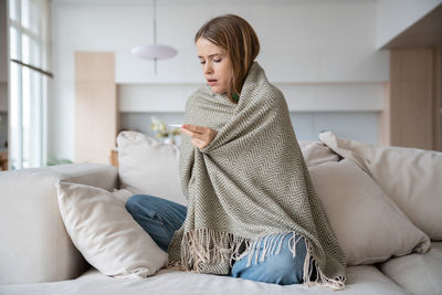 Unhealthy woman looking at thermometer showing high temperature in need of emergency treatment