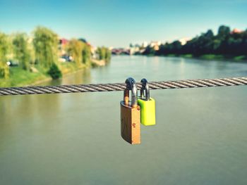 Close-up of padlocks on railing against river