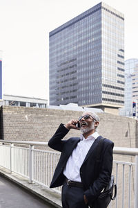 Uk, london, laughing senior businessman on the phone outdoors