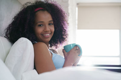 Portrait of a smiling young woman drinking coffee cup