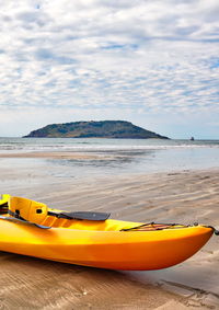 Yellow boats moored on beach against sky