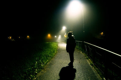 Man playing on illuminated street light at night