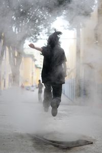 Rear view of man jumping in city