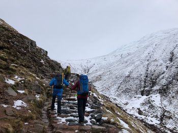 Rear view of hikers moving up on mountain during winter