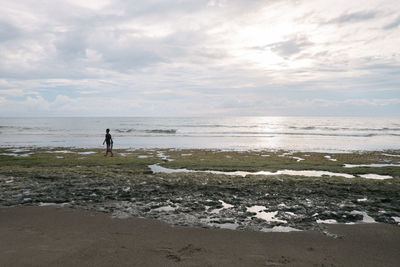 Man standing on beach against sky during sunset