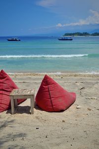 Deck chairs on beach against sky