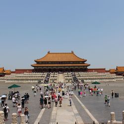 People at temple against clear blue sky