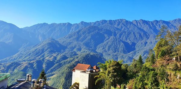 Scenic view of mountains and trees against blue sky