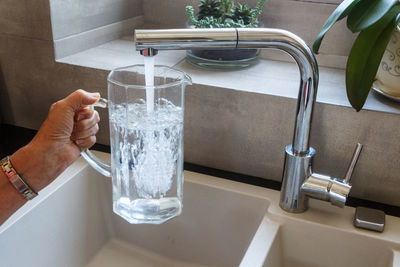 Midsection of person holding drinking glass with water