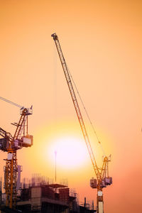 Cranes against sky during sunset