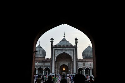 People against clear sky seen through arch