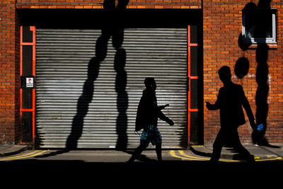 Silhouette people walking in front of building