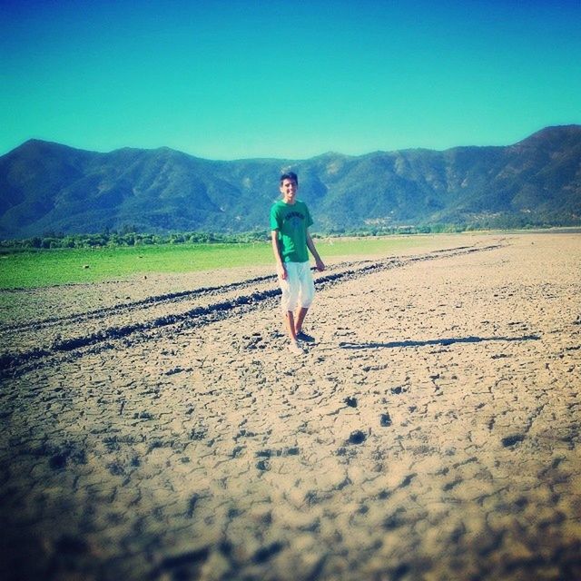 full length, lifestyles, mountain, leisure activity, casual clothing, clear sky, standing, landscape, walking, road, rear view, mountain range, young adult, sky, side view, sunlight, tranquil scene, tranquility