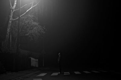Woman standing on footpath at night