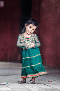 Portrait of smiling young woman standing against wall