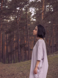 Side view of woman standing in forest