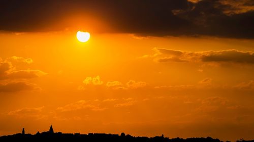 Silhouette landscape against dramatic sky during sunset