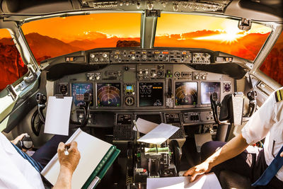 Pilots sitting in cockpit during sunset