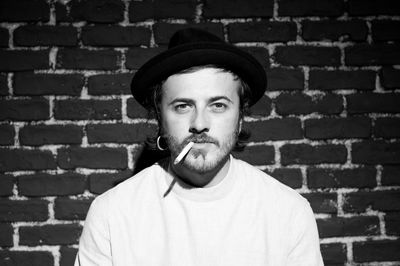 Portrait of man standing against brick wall