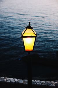 Close-up of illuminated lamp by sea