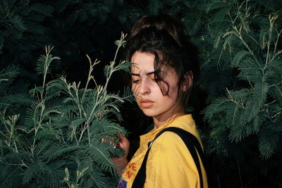 Portrait of young man standing against plants