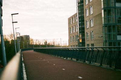 Road by buildings against sky in city