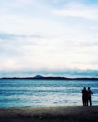 Rear view of people on beach against sky