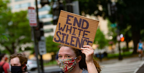 Close-up portrait of woman with text on street in city