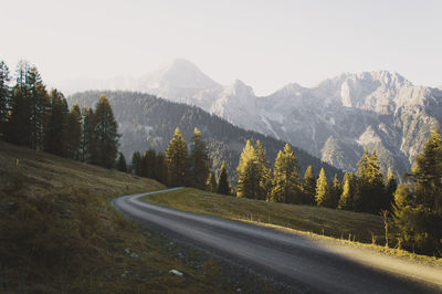 Road amidst trees and mountains against sky