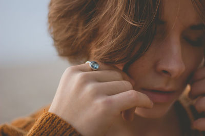 Woman with eyes closed at beach against sky