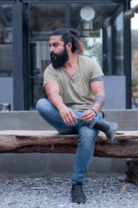 Full length portrait of young man sitting outdoors