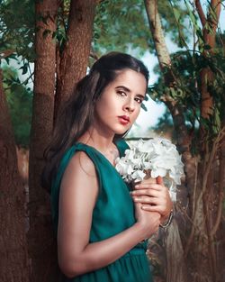 Portrait of beautiful woman against tree trunk