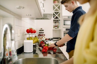 Teenage boy cutting vegetables in kitchen