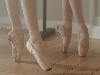 Low section of ballet dancer dancing on hardwood floor