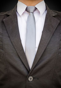 Midsection of businessman standing against black background
