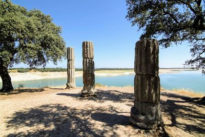 Wooden posts on beach against clear blue sky