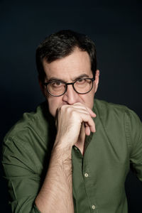 Portrait of man wearing eyeglasses against black background